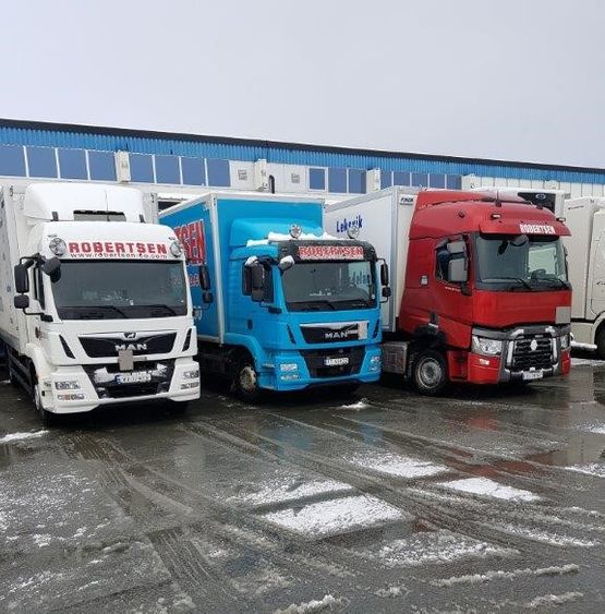 Tre lastebiler på rekke foran blått bygg